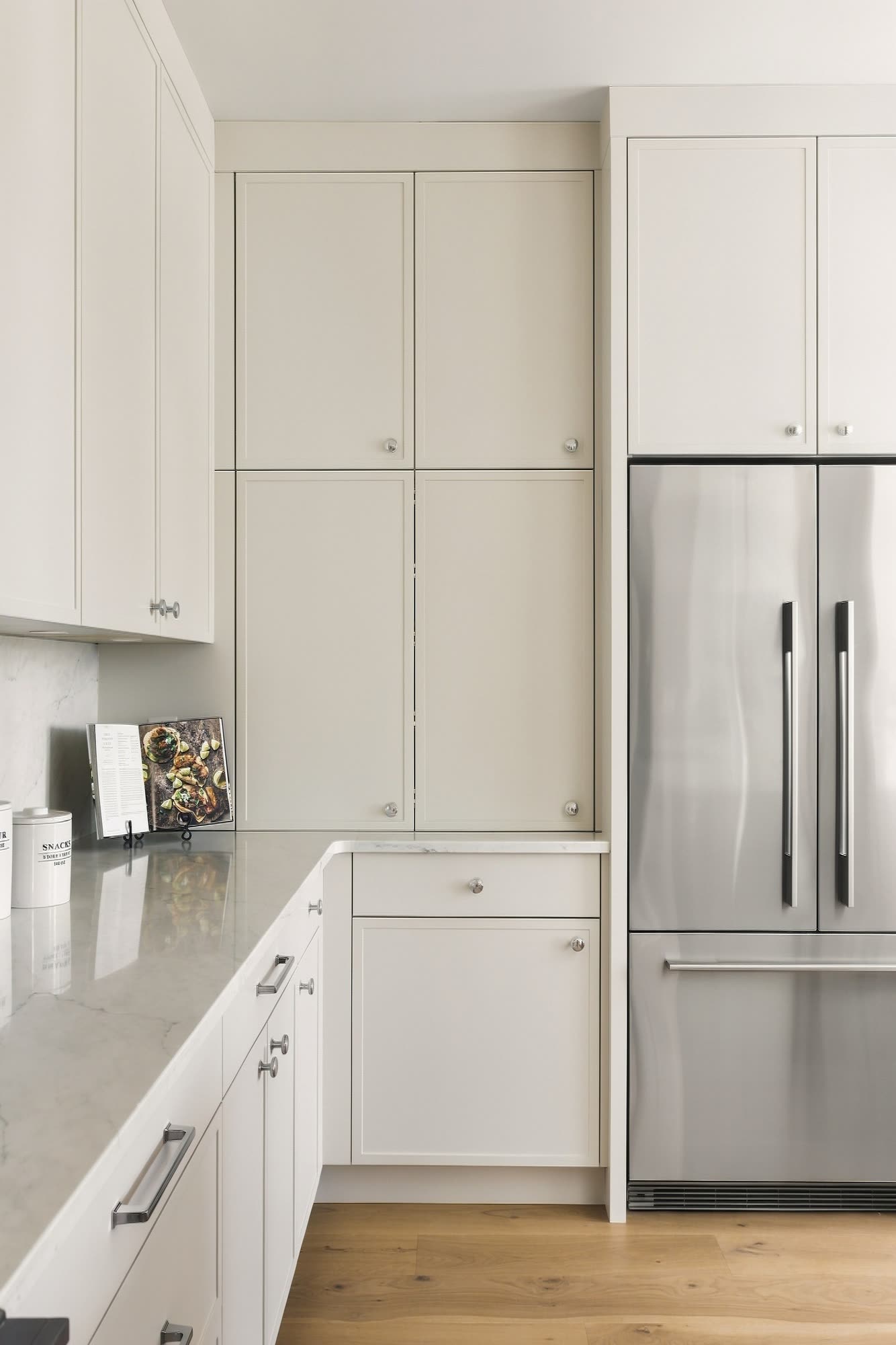 A wall of painted shaker cabinets beside the fridge
