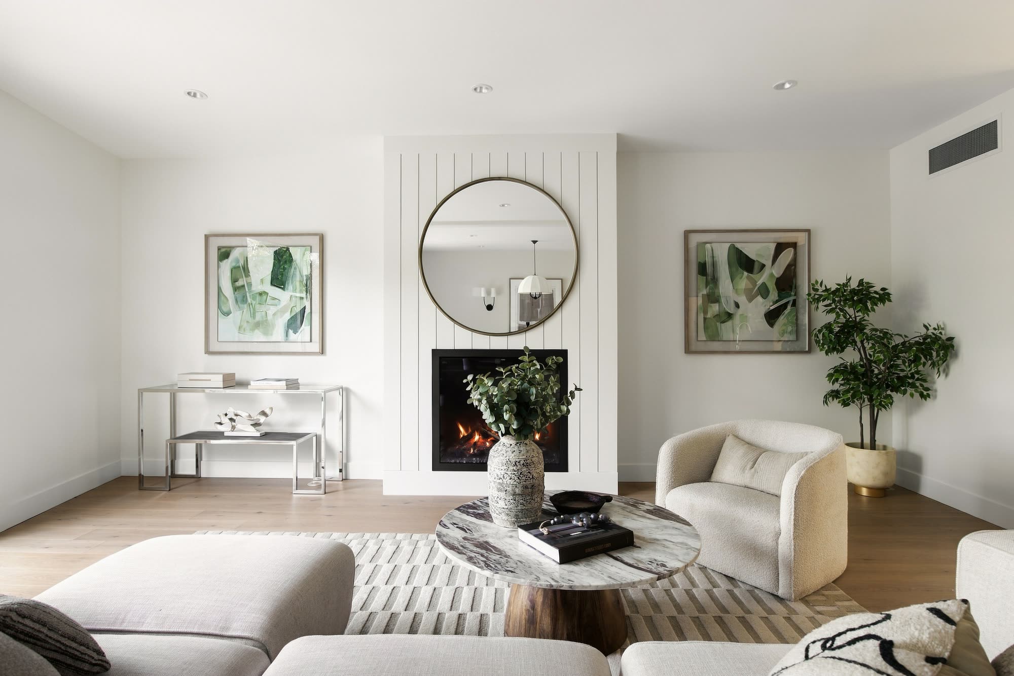 The living room facing the fireplace, with a round mirror and two framed prints