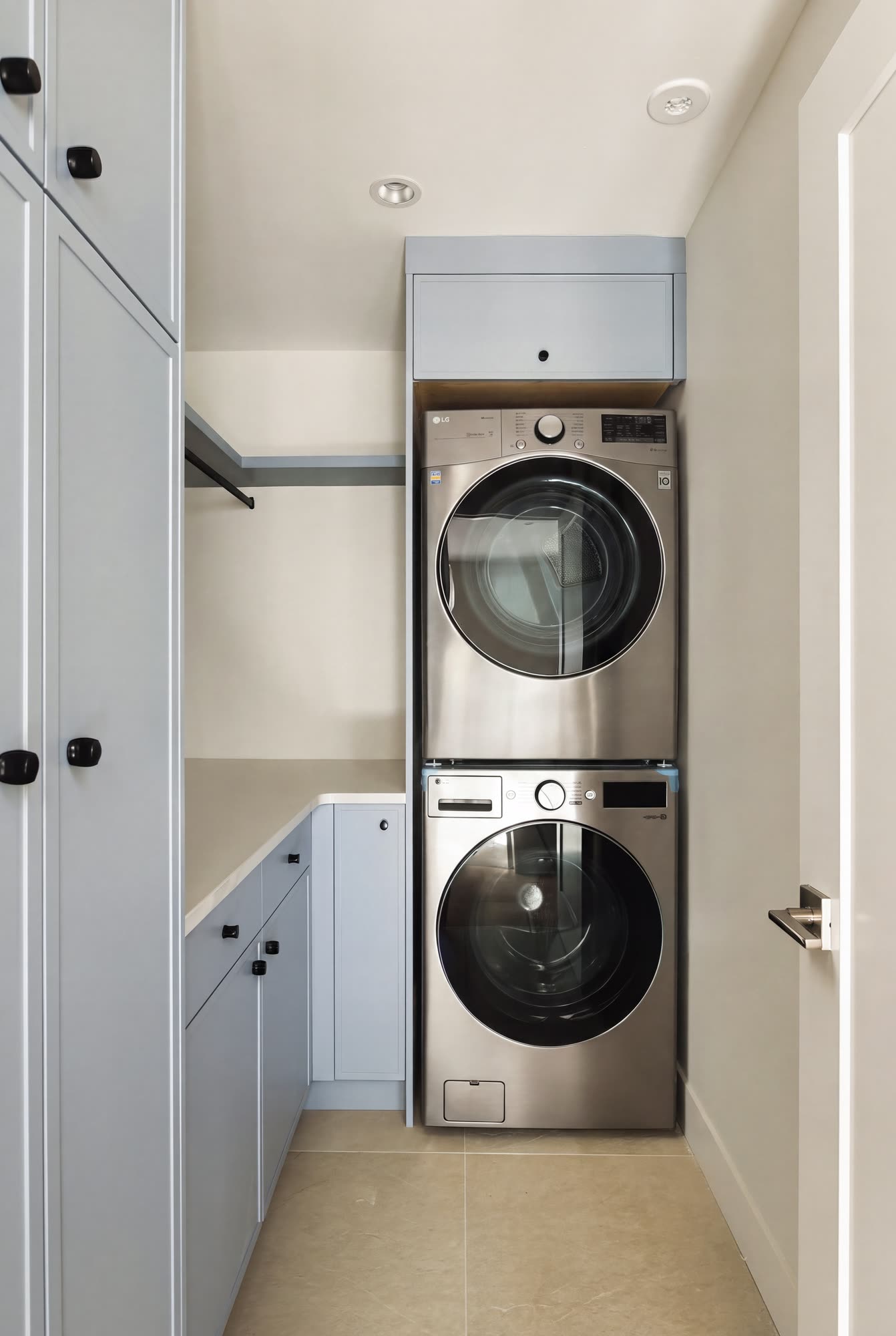 The laundry, with a stacked washer and dryer between pale blue cabinets