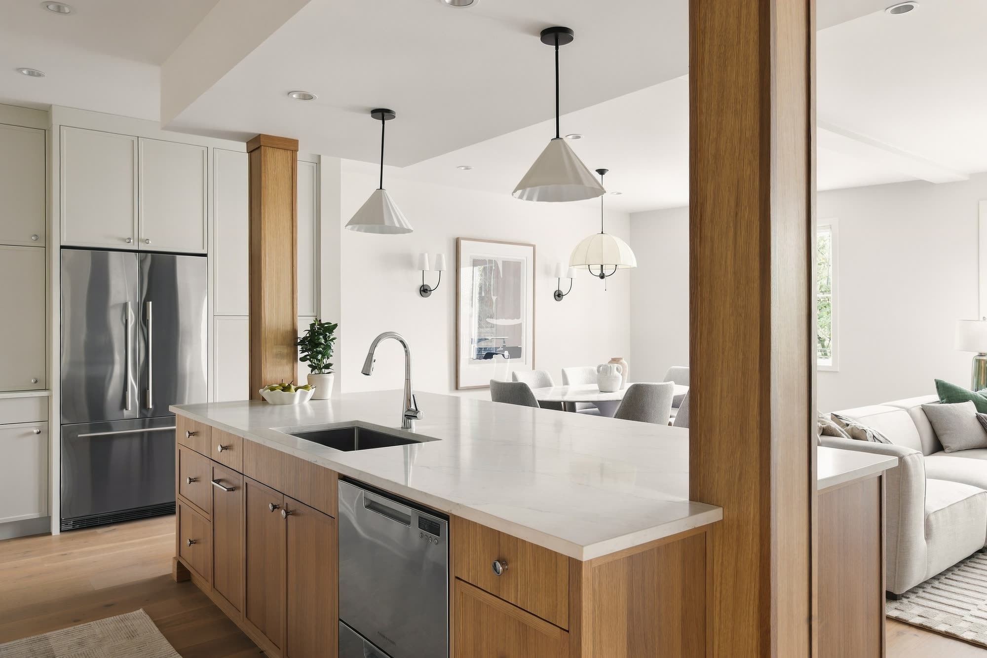 The kitchen island in oak cabinetry, with a quartz top and the fridge behind