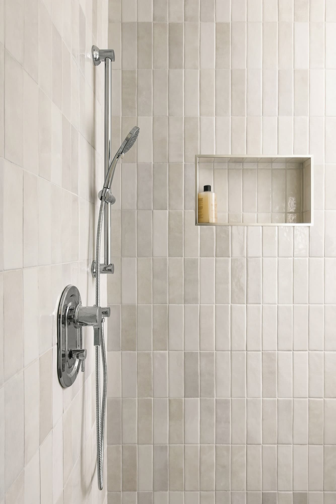 The shower wall in glazed vertical tile, with a niche and a hand shower