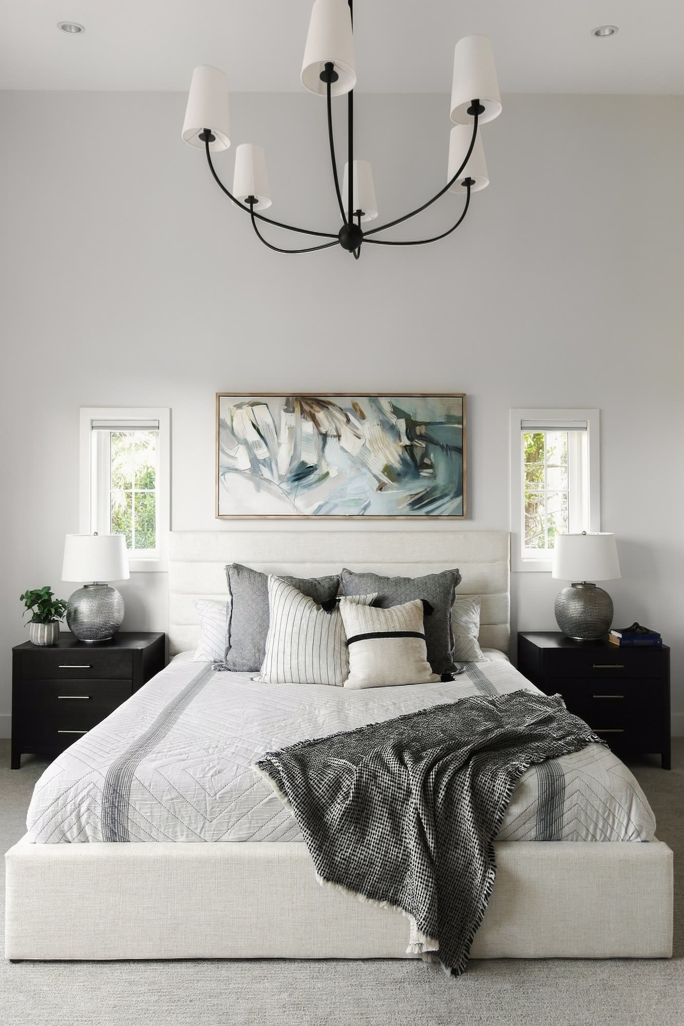 The primary bedroom, with an upholstered bed under a black chandelier