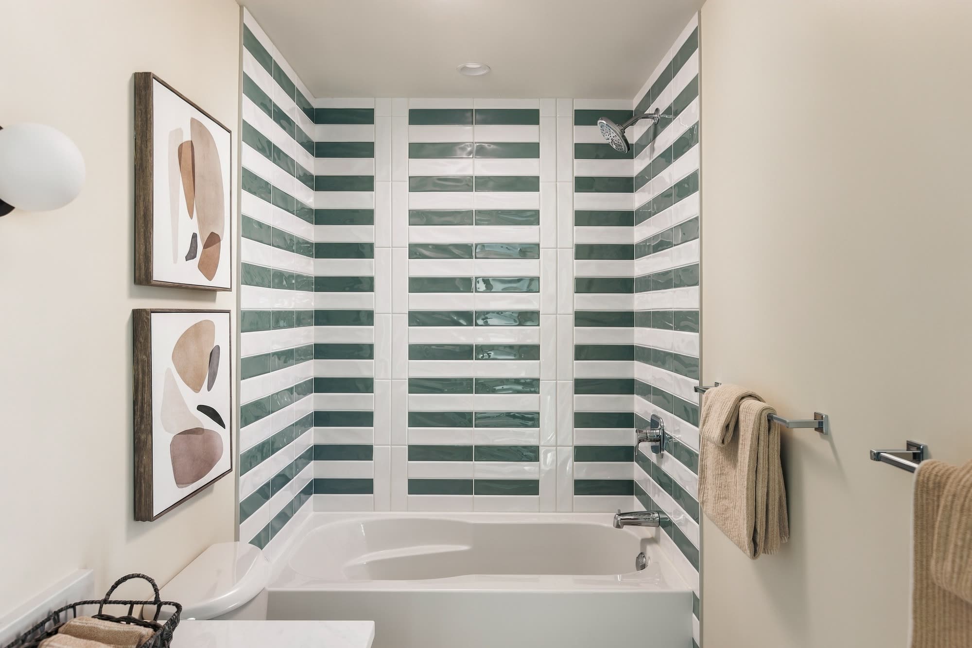 The tub surround in sage and white striped tile