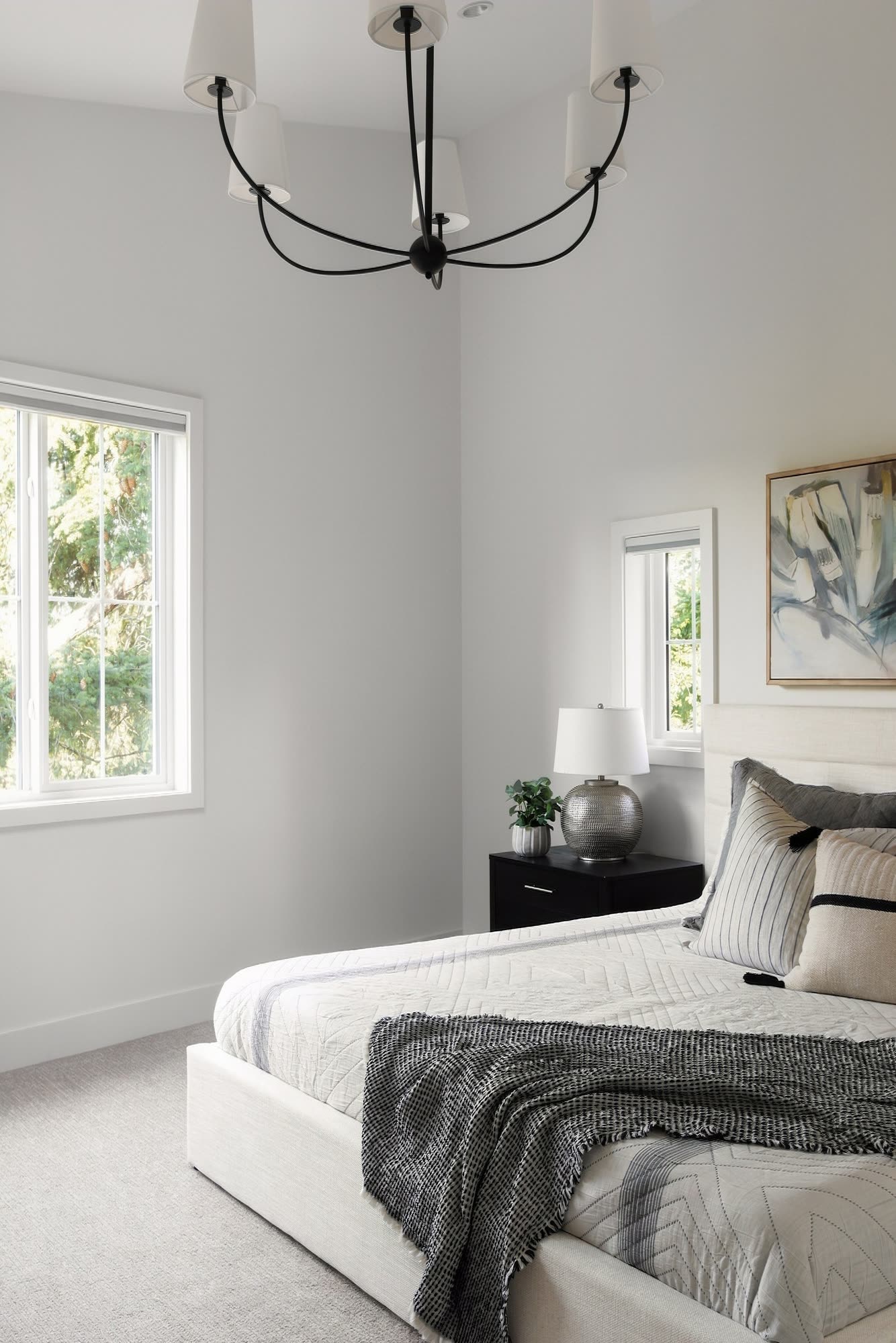The primary bedroom from the corner, under a black chandelier