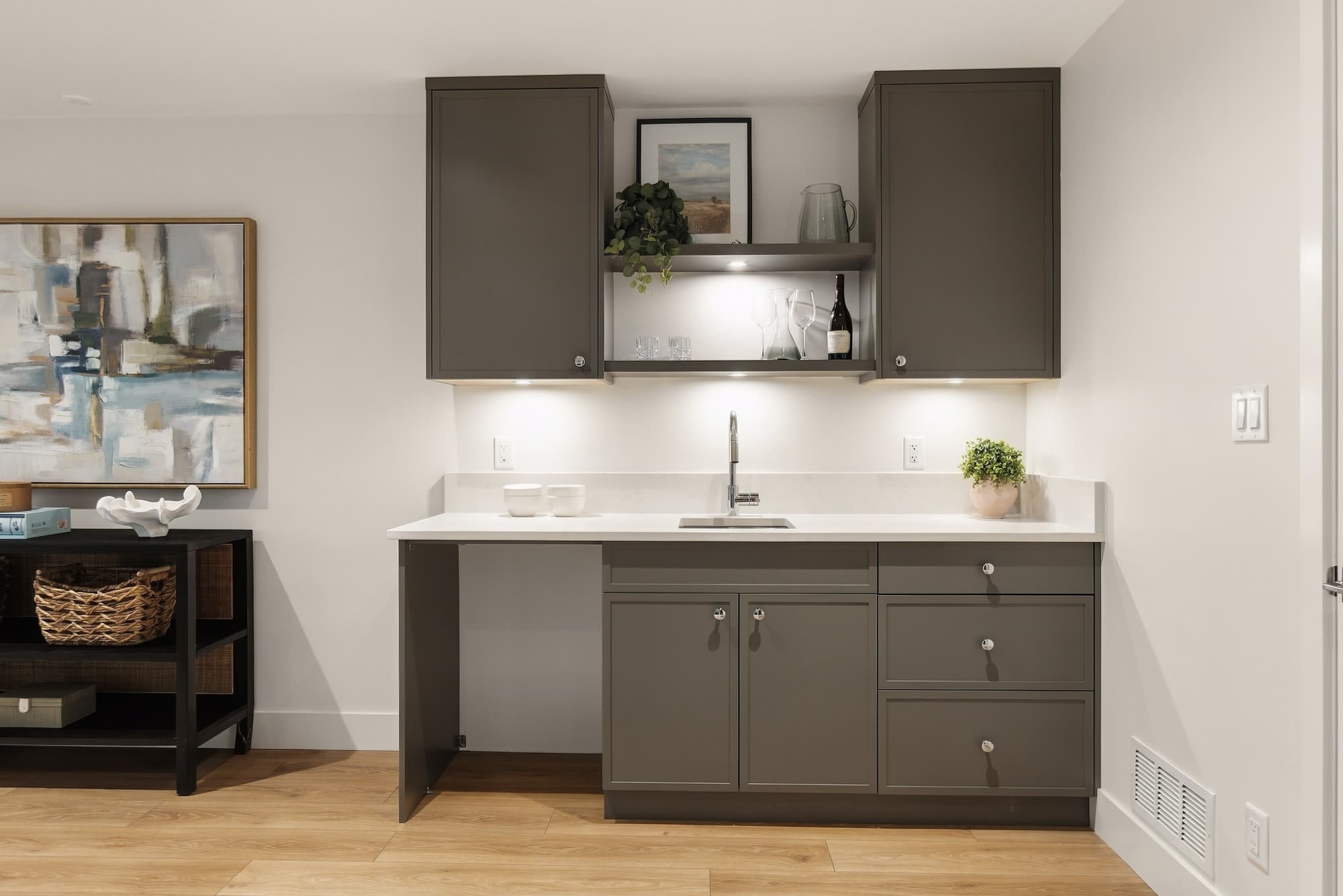 The wet bar, with dark cabinets, open shelves and a quartz counter