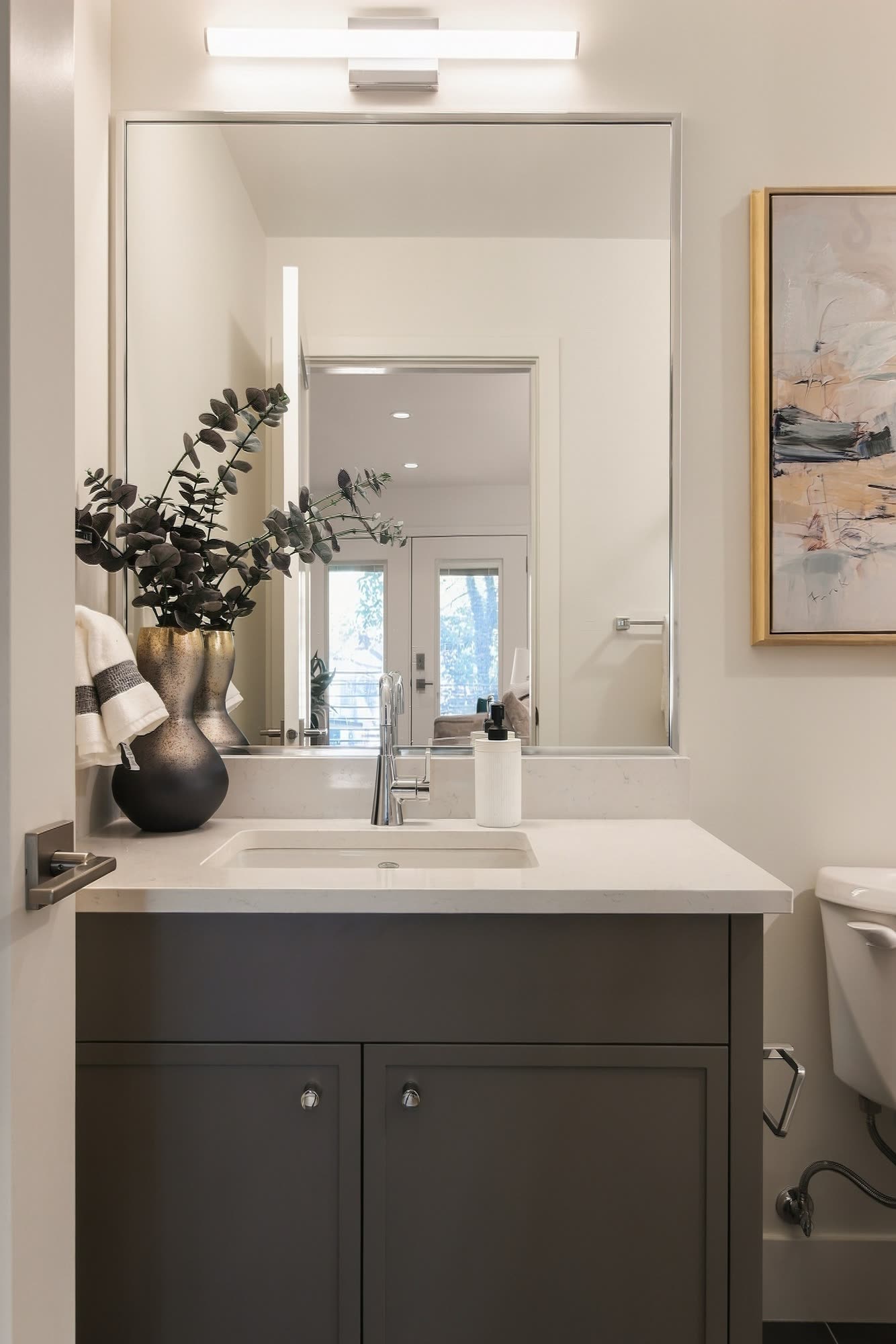 A bathroom with a dark vanity and a large mirror