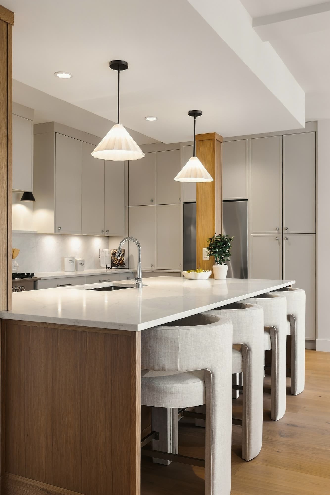 The island from the end, with oak cabinetry, white stools and two cone pendants